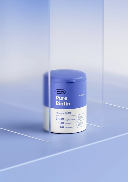 A high-end 3:4 product studio shot featuring a Biotin supplement bottle centered between frosted glass panels.